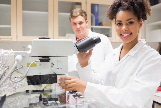 Pretty science student using microscope