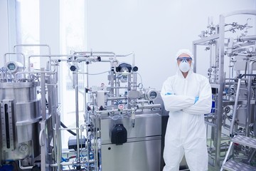 Scientist in protective suit standing with arms crossed