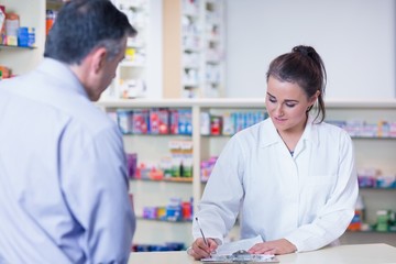 Fototapeta premium Trainee writing prescription in front of a customer
