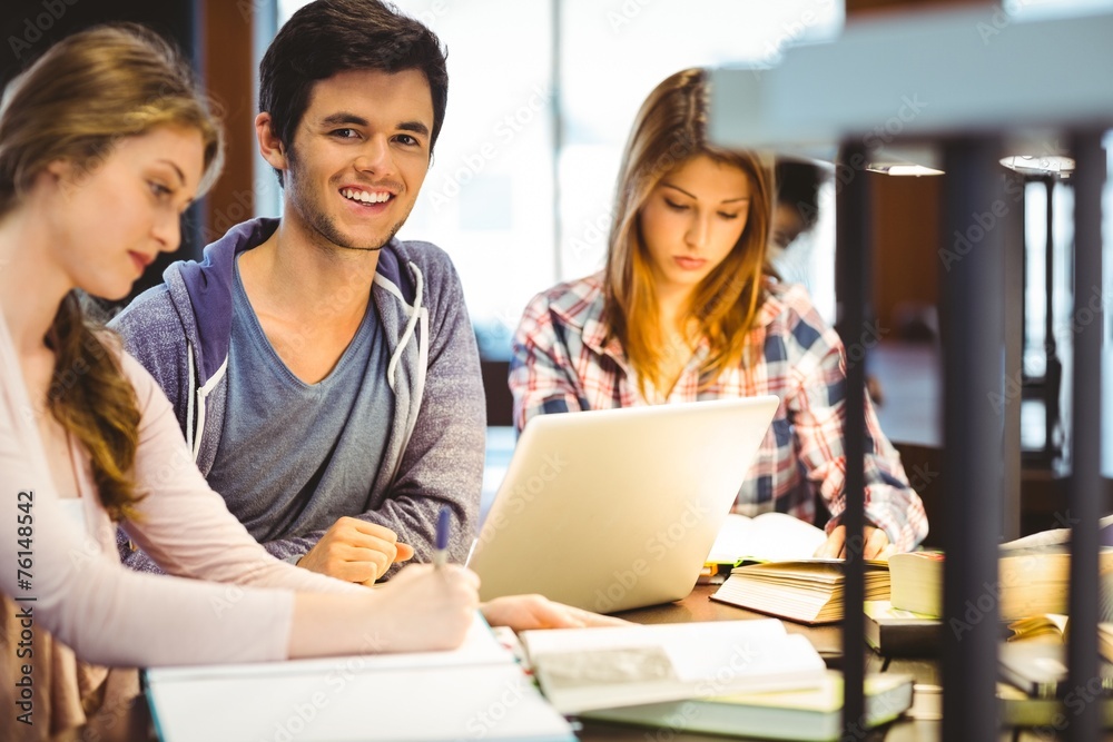 Poster Student looking at camera while studying with classmates