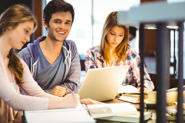 Student looking at camera while studying with classmates