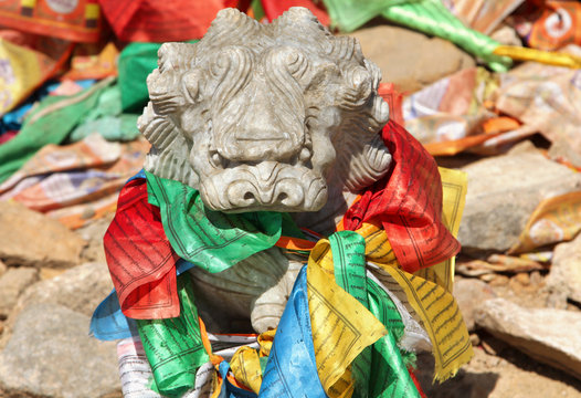 Stone lion with traditional buddhist prayer flags in lamasery