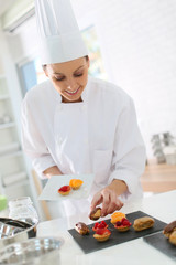 Pastry-cook preparing plate of cake bites