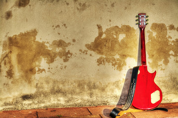 electric guitar leaned on a rustic wall in hdr