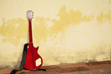 electric guitar leaned on a rustic wall