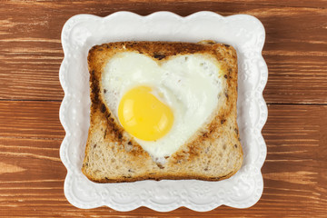 Slice of cereal toast bread with cut out heart shape full egg on