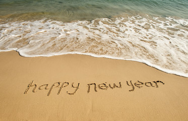 Fototapeta premium happy new year written in the sand