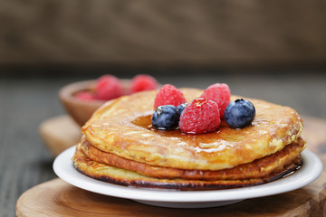 Pancakes with berries and maple syrup, on wooden table