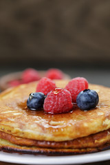 Pancakes with berries and maple syrup, on wooden table