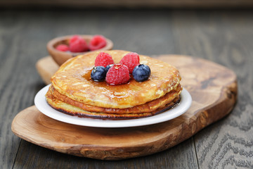 Pancakes with berries and maple syrup, on wooden table