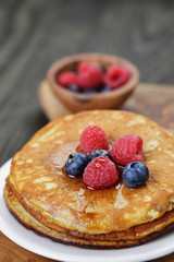 Pancakes with berries and maple syrup, on wooden table