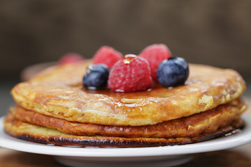 Pancakes with berries and maple syrup, on wooden table