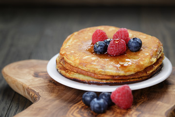 Pancakes with berries and maple syrup, on wooden table