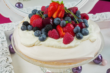 Pavlova cake, decorated with fresh strawberries and blueberries.