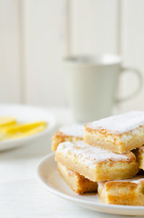 lemon bars on a white plate with slices
