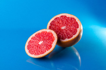 Whole and sliced on half grapefruit on a blue background