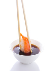 Sushi nigiri in chopsticks dipped in soy sauce isolated