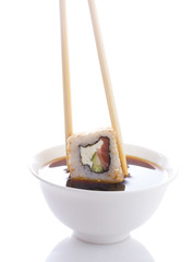 Sushi in chopsticks dipped in soy sauce isolated 