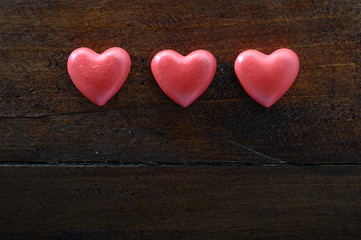 Obraz premium Three red heart on wooden background