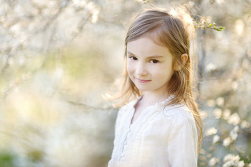 Adorable little girl in blooming cherry garden