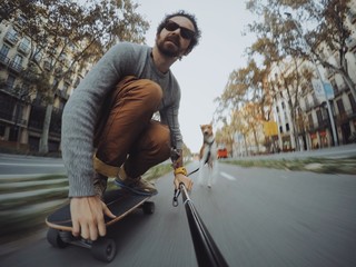 Man rides his longboard followed by his dog