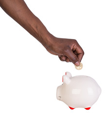 Male hand putting a coin into a piggy bank