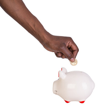 Male Hand Putting A Coin Into A Piggy Bank