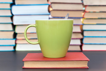 green cup on the red book on a background of books