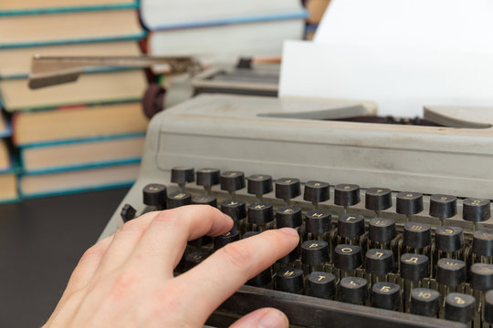 man's hand on an old typewriter