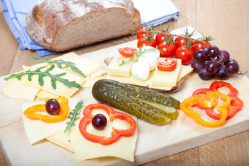 Fototapeta na wymiar Urige bayrische Brotzeit mit Käse, Gemüse, auf Holzbrett