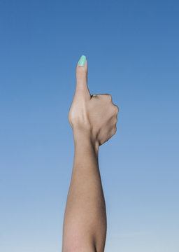 Female hand up in the sky with thumbs up