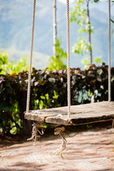 Old wooden vintage garden swing hanging from a large tree.and mo