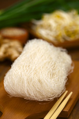Raw rice noodles on wooden board with chopsticks on the side