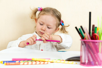 Cute child girl drawing in preschool at table in kindergarten