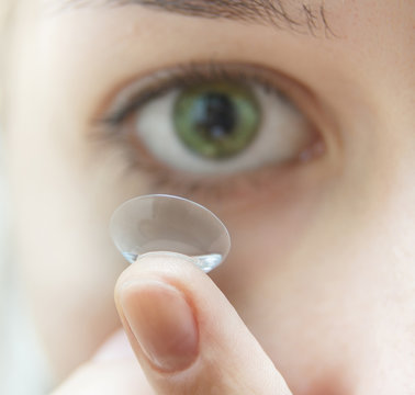 Woman putting contact lens into eye