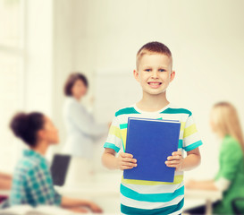 Fototapeta na wymiar smiling little student boy with blue book