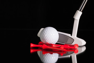 Golf putter and gold equipments on the black glass desk