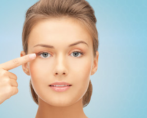 beautiful young woman pointing finger to her eye