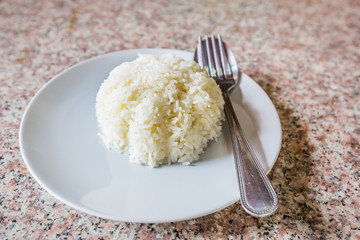 Rice in white dish with silverware. on the marble table