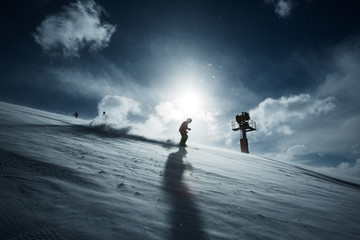 Skifahrer bei Gegenlicht vor Schneekanone
