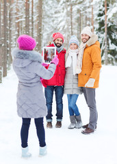 Fototapeta na wymiar smiling friends with tablet pc in winter forest