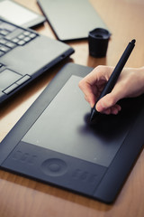 Hand is drawing on a digital graphic tablet with pen