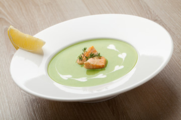 Green broccoli cream soup puree with filleted salmon  and  lemon