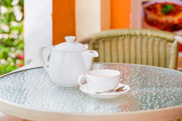 Fototapeta na wymiar Cup of tea and teapot on glass table
