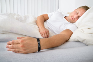 Obraz na płótnie Canvas Young Man Sleeping Wearing Smart Wristband