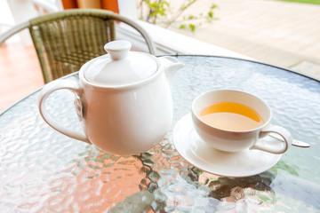 Cup of tea and teapot on glass table