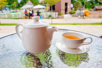 Cup of tea and teapot on glass table