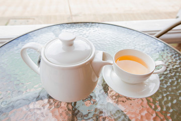 Cup of tea and teapot on glass table