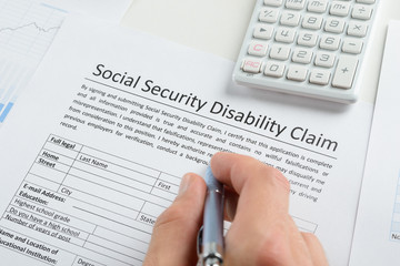 Person Hand With Pen Filling Social Security Disability Form