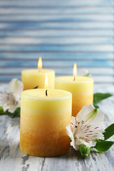 Beautiful candles with flowers on wooden background